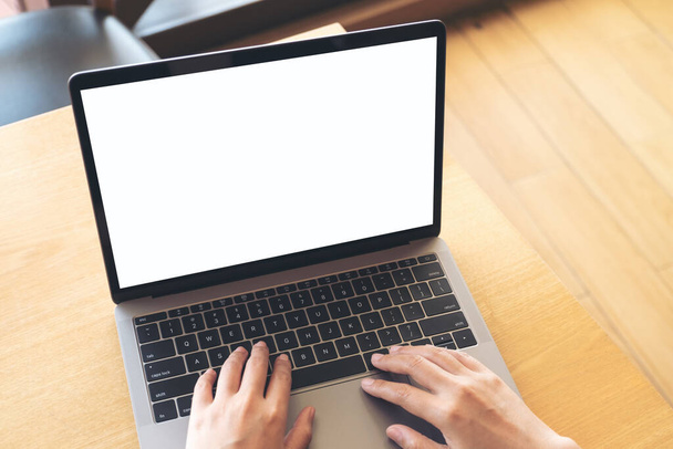 Kafede boş beyaz ekranla dizüstü bilgisayarda yazı yazan ve kullanan ellerin en üst görünüm görüntüsü - Fotoğraf, Görsel
