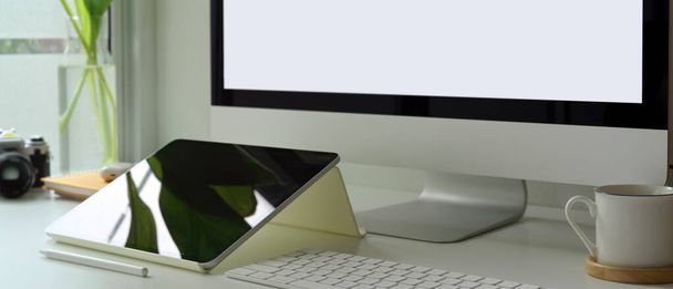 Opname van eenvoudig bureaublad met mock-up computer, digitale tablet, camera en kantoorbenodigdheden  - Foto, afbeelding