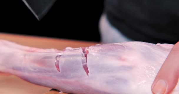 Ein professioneller Koch macht Scheiben auf roher Lammkeule mit Messer auf hölzernem Becherbrett.  - Filmmaterial, Video