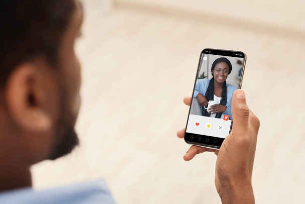 Chico negro usando teléfono celular con perfil femenino en la pantalla
 - Foto, Imagen