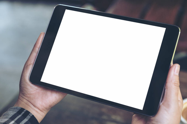 Imagem Mockup de mãos segurando tablet preto pc com tela de desktop branca em branco no café - Foto, Imagem