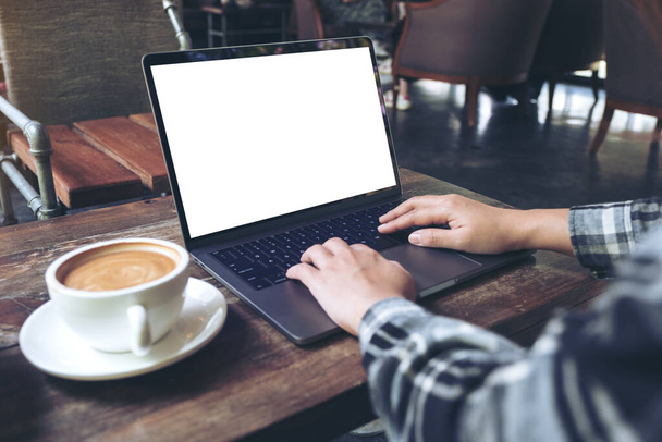 Макет изображения руки с помощью ноутбука с чистым белым экраном рабочего стола с чашкой кофе на деревянном столе в кафе
 - Фото, изображение