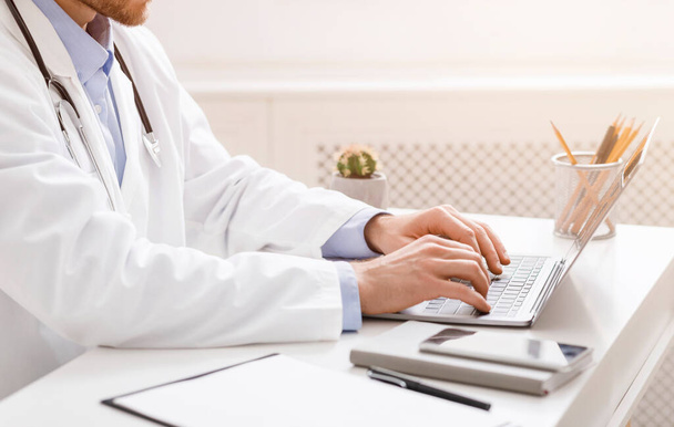 Лікар консультує пацієнтів через Інтернет, друкуючи на ноутбуці
 - Фото, зображення