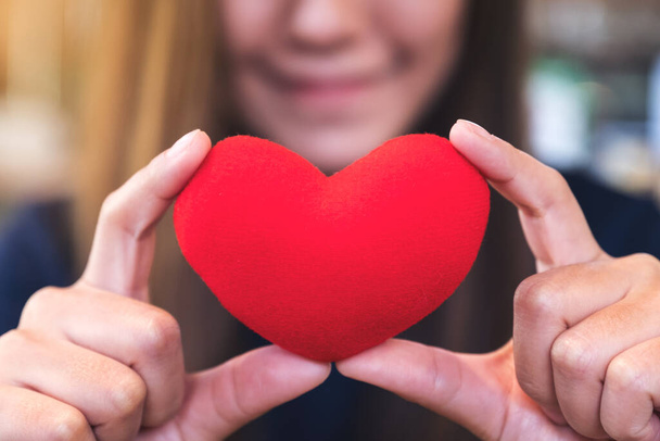 Κοντινό πλάνο εικόνα μιας ευτυχισμένης γυναίκας που κρατά ένα κόκκινο σημάδι της καρδιάς με αίσθημα αγάπης - Φωτογραφία, εικόνα