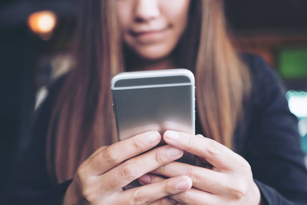 Closeup image of a woman holding , using and looking at smart phone  - Photo, Image