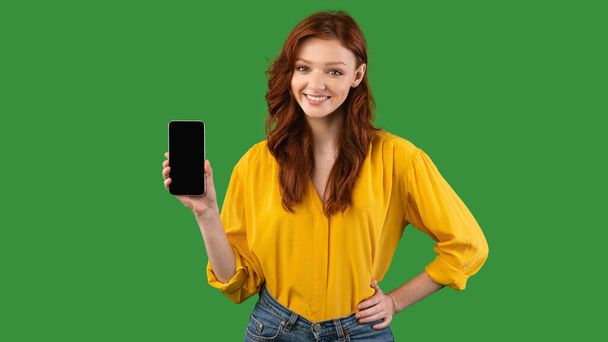 緑の背景に携帯電話の空の画面を示す千年紀の女の子,パノラマ - 写真・画像