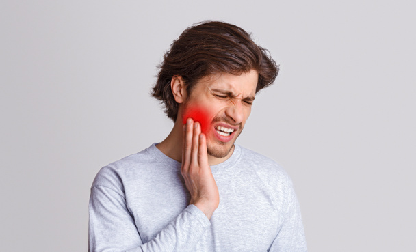 Kestä kipua. Surullinen mies kärsii kipua hampaissaan ja painaa kädestä punaiseen pilkkuun - Valokuva, kuva