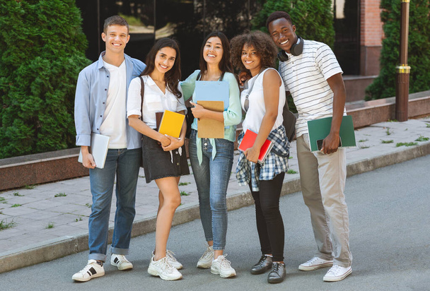 Grupo multiétnico de estudiantes al aire libre en el campus escolar con libros de trabajo
 - Foto, imagen