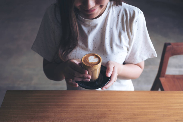 Closeup image of an Asian woman holding a coffee cup before drinking with feeling good in cafe - Photo, Image