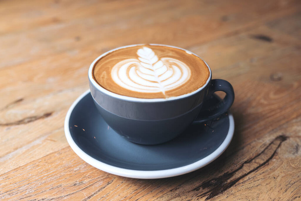 Imagen de primer plano de una taza azul de café latte caliente con arte latte en la mesa de madera vintage en la cafetería
 - Foto, imagen