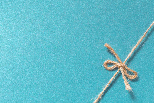 ツイン弓ギフトの背景。天然ジュートロープ弓結び目上の光沢のある青い紙  - 写真・画像