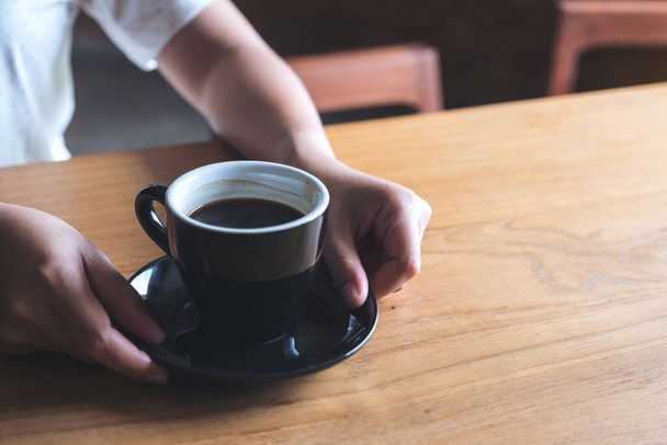 Immagine da primo piano delle mani della donna che tengono e danno una tazza di caffè caldo sul tavolo vintage in legno - Foto, immagini