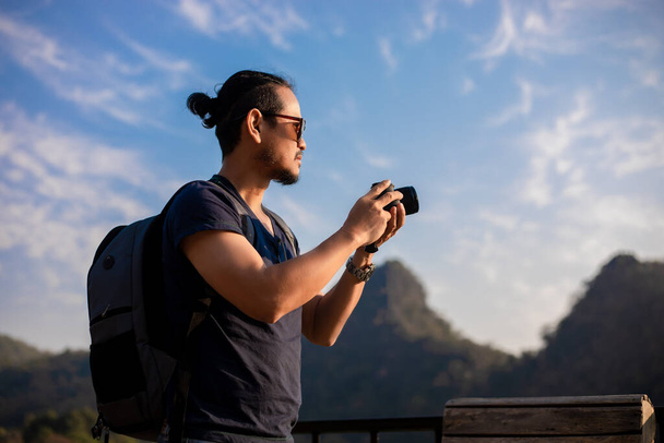 Ázsiai férfi turista használja a fényképezőgépet, hogy a képek a táj és a hegy.Relax ideje nyaralás koncepció utazás - Fotó, kép