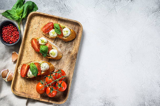 Sandwiches mit Tomaten, Mozzarella und Basilikum. italienische Vorspeise, Antipasto. grauer Hintergrund. Ansicht von oben. Kopierraum. - Foto, Bild