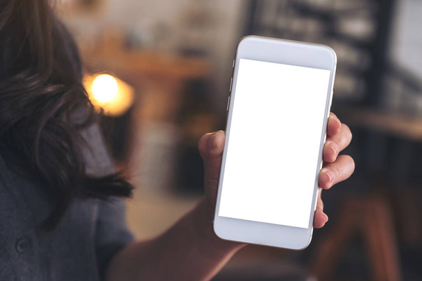 Attrappe einer Frau, die ein weißes Handy mit leerem Bildschirm im Café hält und zeigt - Foto, Bild