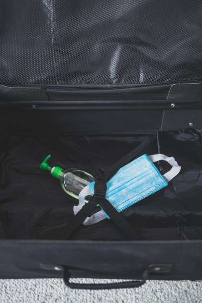 travel industry and flying during covid-19, carry-on luggage with surgical face mask and hand sanitizer for virus protection inside - Foto, immagini