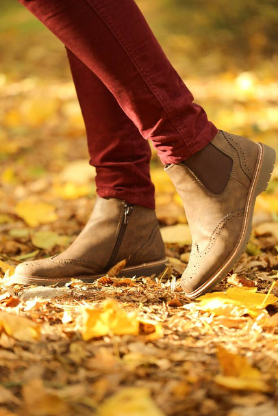 Ősszel. lábak barna szarvasbőr csizma egy elmosódott sárga levelek háttér - Fotó, kép