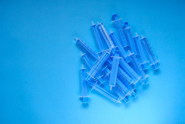 Medizin und Gesundheitskonzept. Blaue Plastikspritzen in Großaufnahme auf blauem Hintergrund - Foto, Bild