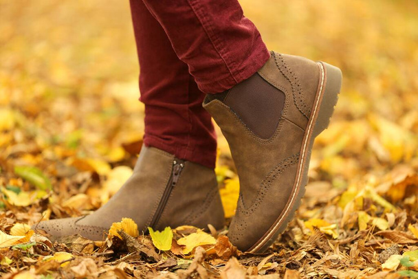 Осеннее время. ноги в коричневых замшевых сапогах на размытом желтом фоне листьев
 - Фото, изображение