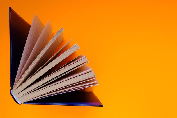 Books with spread out pages on a bright orange background - Photo, Image