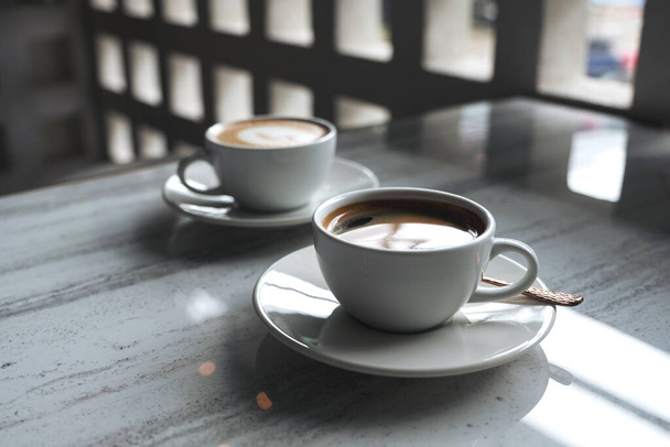 Closeup image of two white cups of hot coffee on table in cafe - Foto, imagen