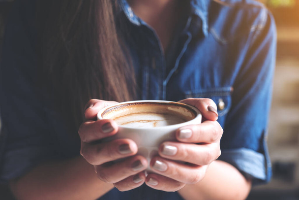 Closeup image of a woman holding a cup of coffee before drinking with feeling good and relaxed  in cafe - Foto, Imagem