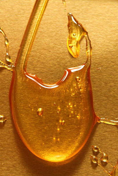 Miel dégoulinant sur un fond doré. Texture du miel - Photo, image