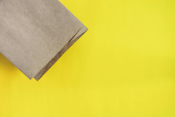 Attrappe der leeren braunen Papiereinkaufstasche isoliert gelben Hintergrund, Kopierraum, Ansicht von oben, flache Lage - Foto, Bild