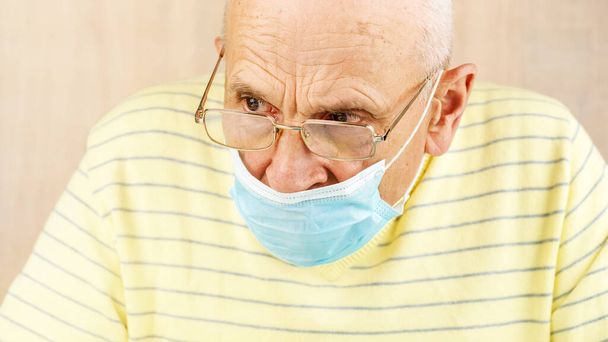 senior man in blue face mask and glasses looks aside closeup - Foto, Bild