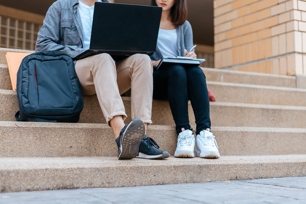  teenager sitting on stair at college campus with school books and a laptop computer doing homework. Education concept. - Photo, image