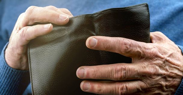 pensioner in blue sweater hands hold old black wallet - Foto, imagen