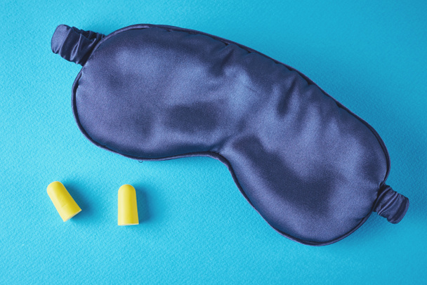 Insomnia and sleeping problem concept.Sleeping mask and ear plugs on blue background, top view - Photo, Image
