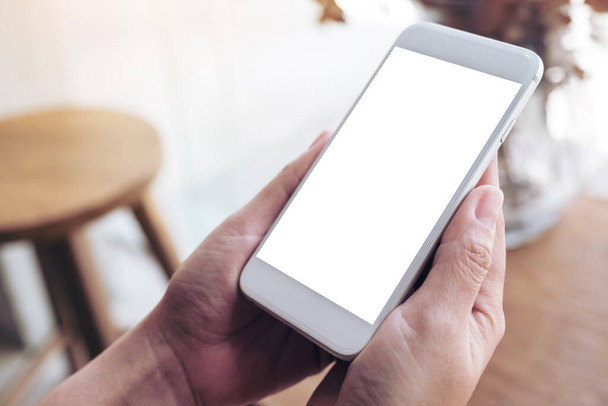 Imagem Mockup de mãos segurando telefone celular branco com tela de desktop em branco no café - Foto, Imagem