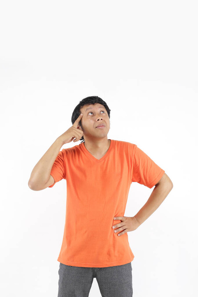 άνθρωπος asia σκέψης με κενό χώρο χρησιμοποιώντας πορτοκαλί t-shirt - Φωτογραφία, εικόνα