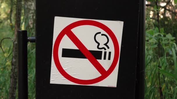 знак Курение запрещено на черном мусорном баке в лесу. - Кадры, видео