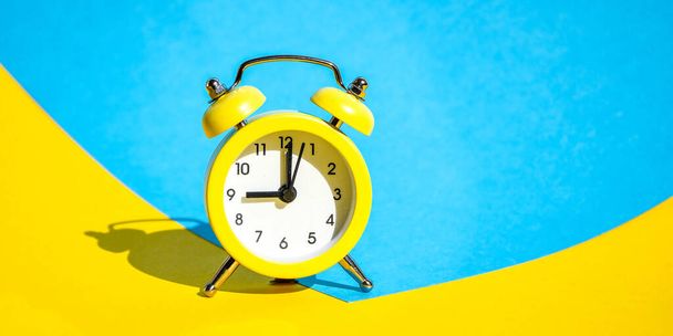 選択的なフォーカスを持つ青と黄色の背景に黄色のヴィンテージ目覚まし時計、テキストのためのコピースペース、時間の概念は、遅延、朝の上昇、任命会議、リングツインベルヴィンテージ古典的な目覚まし時計、人生の残りの時間良い朝 - 写真・画像