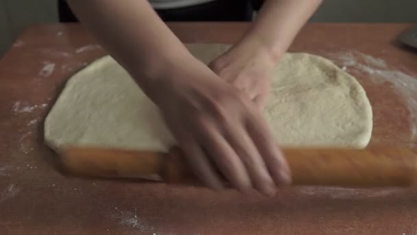 A nők kezei gurítják a tésztát a konyhaasztalon. Női kezek sodrófával - Felvétel, videó