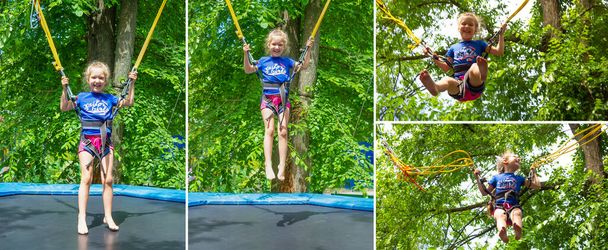 Het lachende vrolijke meisje springt met bungee in trampoline op park tegen groene bomen - Foto, afbeelding