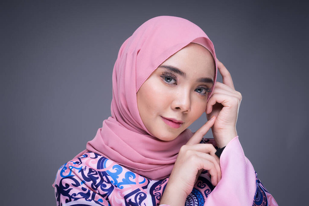 Beautiful Muslim female model wearing modern apparel with hijab, a urban lifestyle apparel for Muslim women isolated on grey background. Beauty and hijab fashion concept. Headshot portrait. - Photo, Image