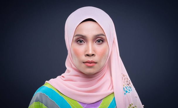 Retrato en la cabeza de una hermosa modelo musulmana vestida de kaftan pastel con hiyab, un moderno estilo de vida urbano para mujeres musulmanas aisladas sobre fondo gris. Belleza y hijab concepto de moda
. - Foto, Imagen