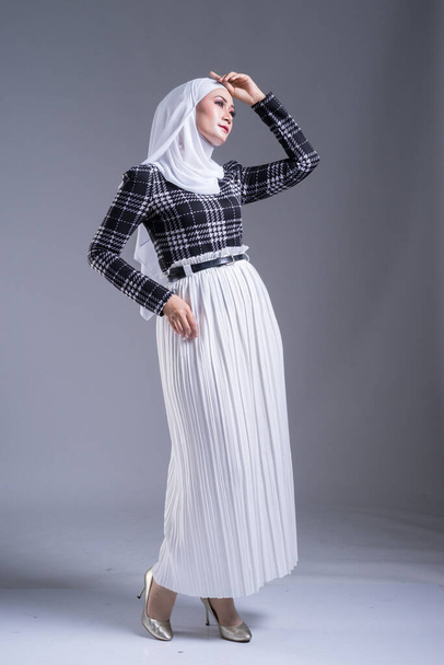 Güzel bir Müslüman kadın modelin, tesettürlü ve gri arka planda gündelik giyimli tam boy portresi. Başörtüsü ve Müslüman yaşam tarzı konsepti - Fotoğraf, Görsel