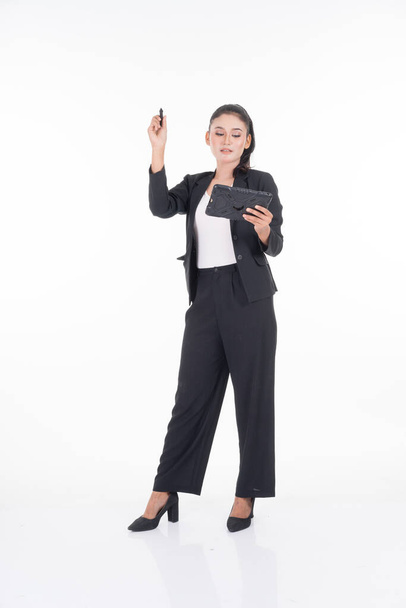 Μια ελκυστική γυναίκα που φοράει επαγγελματική ενδυμασία κρατώντας ένα δισκίο με διάφορες στάσεις που απομονώνονται σε λευκό φόντο. Κατάλληλο για εργασίες αφαίρεσης εικόνας και χειραγώγησης για θέματα τεχνολογίας, επιχειρήσεων ή χρηματοδότησης - Φωτογραφία, εικόνα