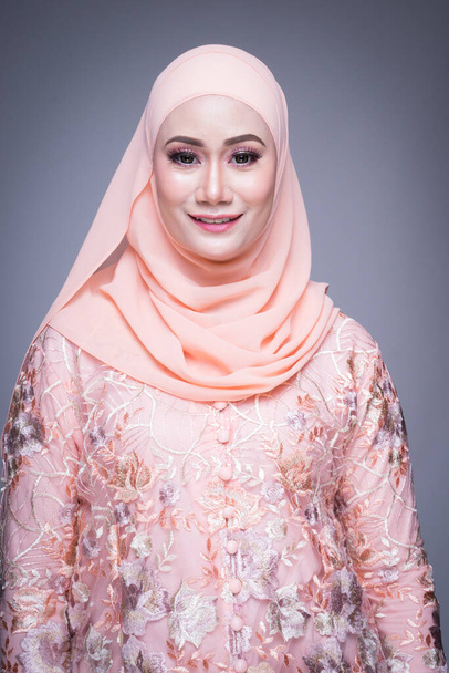 Mooi vrouwelijk model in moderne kurung en hijab, een moderne levensstijl kleding voor moslimvrouwen geïsoleerd op grijze achtergrond. Schoonheid en hijab mode concept. Halve lengte portret - Foto, afbeelding