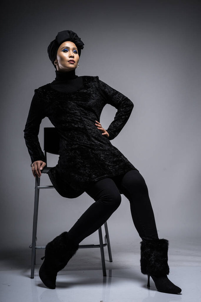 Retrato de alta moda de uma mulher asiática em um top preto e calças com um turbante em fundo cinza. Conceito editorial de moda para moda hijab. Comprimento total
 - Foto, Imagem