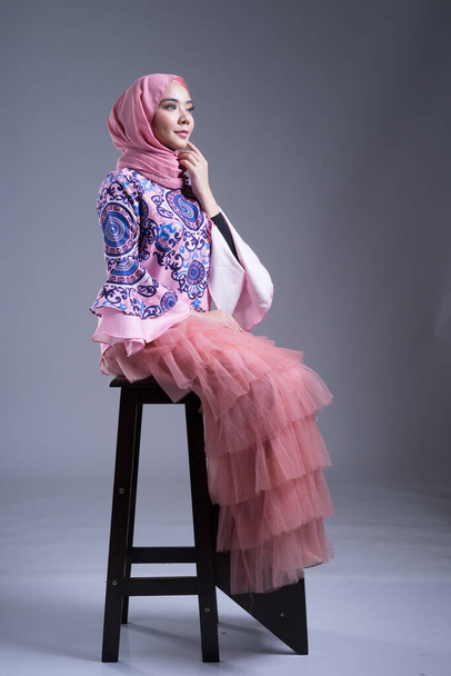 Full length portrait of a beautiful female model wearing traditional dress and hijab, a lifestyle apparel for Muslim women on grey background. Idul Fitri and hijab fashion concept. - Foto, imagen