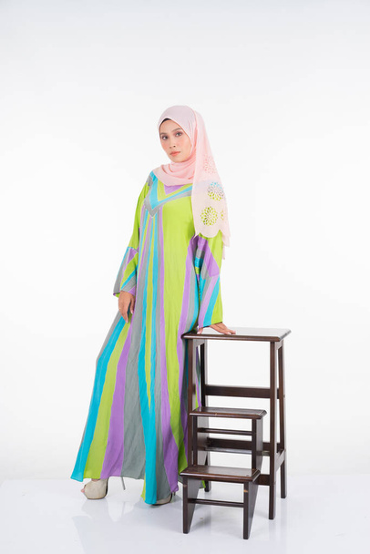 Hermosa modelo femenina con un batik kaftan pastel / caftán, un vestido tradicional para mujeres musulmanas aisladas sobre fondo blanco. Estilo musulmán femenino hijab moda estilo de vida retrato concepto
. - Foto, Imagen