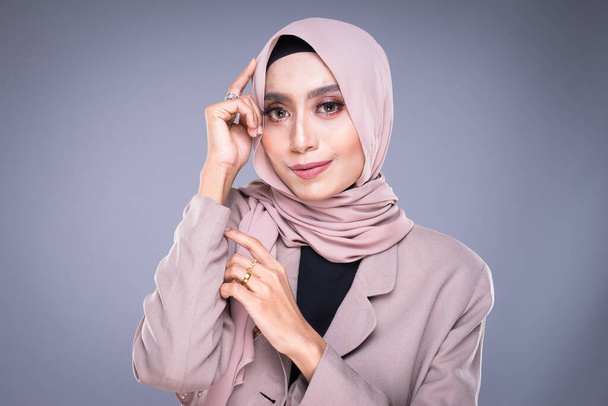 Фото красивой мусульманской модели в хиджабе и офисной одежде на сером фоне. Хиджаб и мусульманский стиль жизни
 - Фото, изображение