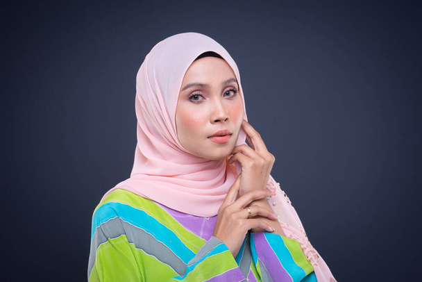 πορτραίτο ενός όμορφου γυναικείου μουσουλμανικού μοντέλου που φοράει παστέλ καφτάνι με χιτζάμπ, μια σύγχρονη αστική ενδυμασία τρόπου ζωής για τις μουσουλμάνες γυναίκες που απομονώνονται σε γκρι φόντο. Έννοια μόδας ομορφιάς και χιτζάμπ. - Φωτογραφία, εικόνα