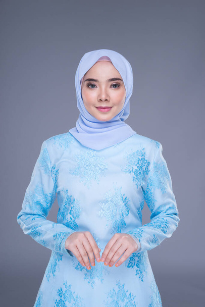 Modelo feminino muçulmano bonito vestindo azul pastel moderno kurung com hijab, um vestuário de estilo de vida urbano para mulheres muçulmanas isoladas em fundo cinza. Beleza e hijab conceito de moda. Metade do comprimento
 - Foto, Imagem