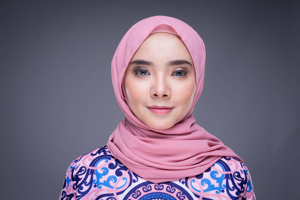 Schöne muslimische Model in moderner Kleidung mit Hijab, einem urbanen Lifestyle-Kleidungsstück für muslimische Frauen isoliert auf grauem Hintergrund. Schönheits- und Hijab-Modekonzept. Kopfschuss-Porträt. - Foto, Bild